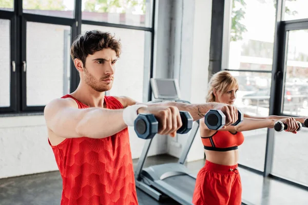 Enfoque selectivo de hombre y mujer haciendo ejercicio con pesas en el gimnasio - foto de stock