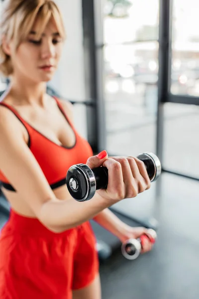 Selective focus of sportive woman working out with dumbbells in sports center — Stock Photo