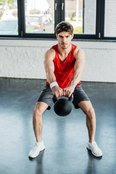 Athletic man exercising with heavy dumbbell in sports center — Stock Photo