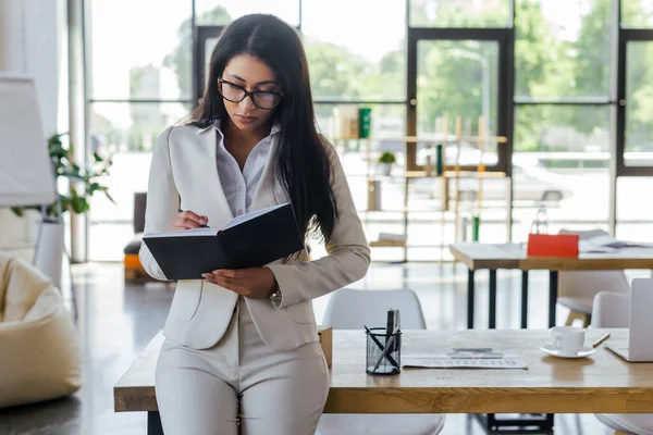 Hermosa mujer de negocios en gafas mirando cuaderno en la oficina — Stock Photo