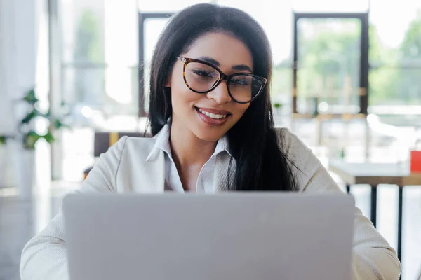 Selektiver Fokus der gut gelaunten Geschäftsfrau in Brille mit Laptop — Stockfoto