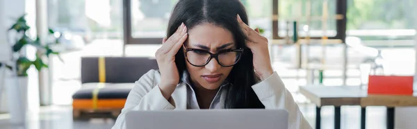 Panoramic shot of stressed businesswoman in glasses touching temples — Stock Photo