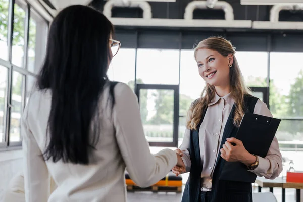 Foyer sélectif de femme d'affaires heureuse serrant la main avec un collègue au bureau — Photo de stock