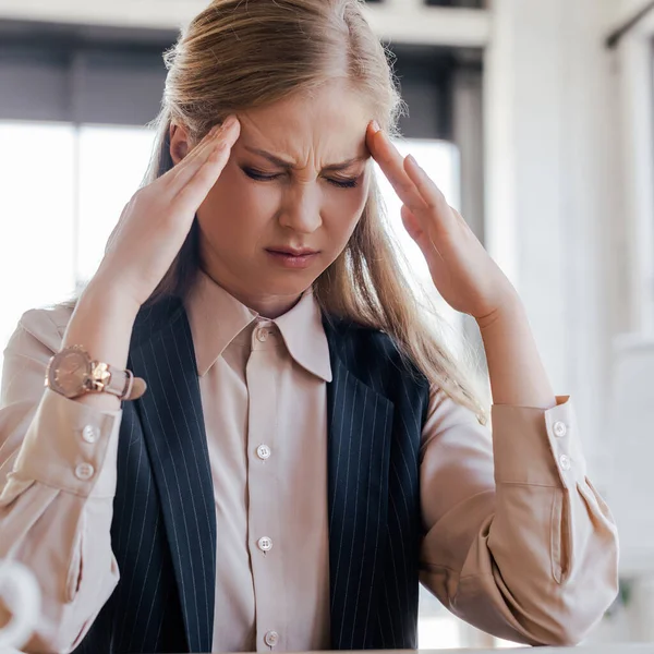 Tired woman touching temples while suffering from migraine — Stock Photo