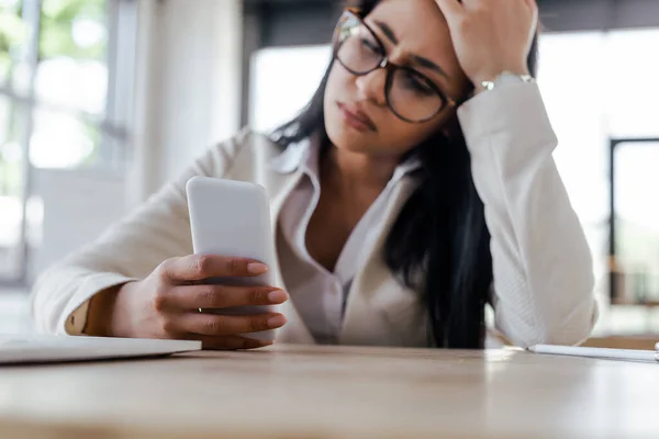 Foyer sélectif de femme d'affaires bouleversée en utilisant smartphone et geste au bureau — Photo de stock