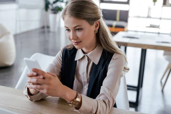 Hermosa mujer de negocios usando teléfono inteligente en la oficina - foto de stock