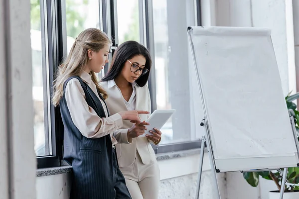 Enfoque selectivo de la mujer de negocios que apunta con el dedo a la tableta digital cerca de compañero de trabajo atractivo en gafas — Stock Photo