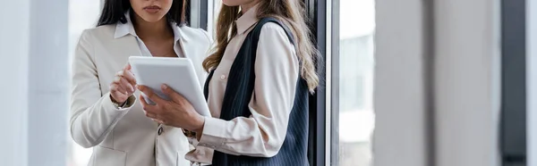 Panoramic concept of businesswoman holding digital tablet near coworker — Stock Photo