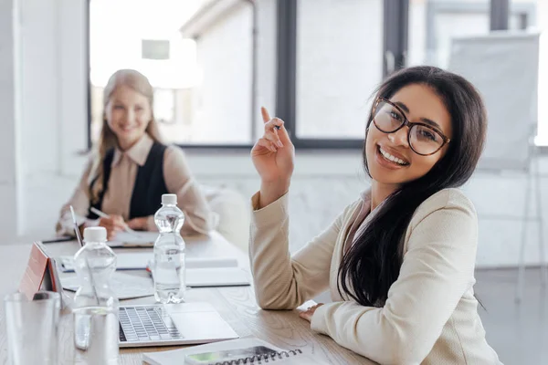 Вибірковий фокус щасливої бізнес-леді в окулярах, вказуючи пальцем в офісі — стокове фото