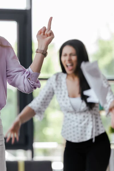 Enfoque selectivo de la mujer de negocios mostrando el dedo medio a su compañero de trabajo enojado - foto de stock