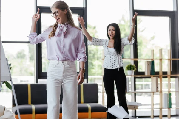 Selective focus of displeased businesswoman showing middle finger to angry coworker — Stock Photo