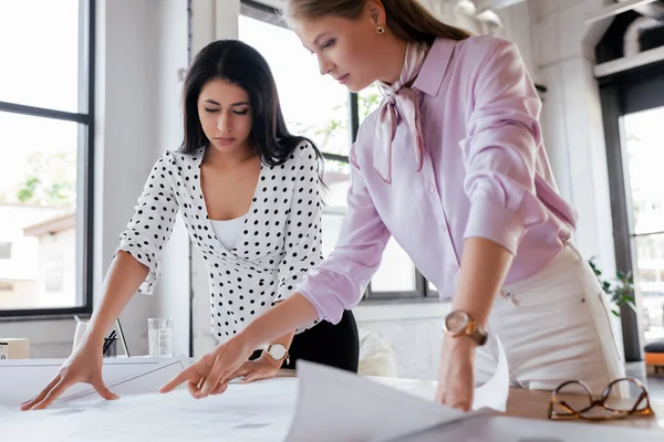 Enfoque selectivo de las mujeres de negocios mirando los planos en la oficina - foto de stock