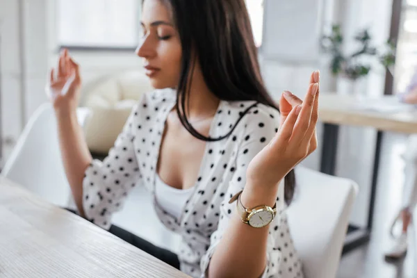 Enfoque selectivo de hermosa mujer de negocios con los ojos cerrados meditando en la oficina - foto de stock