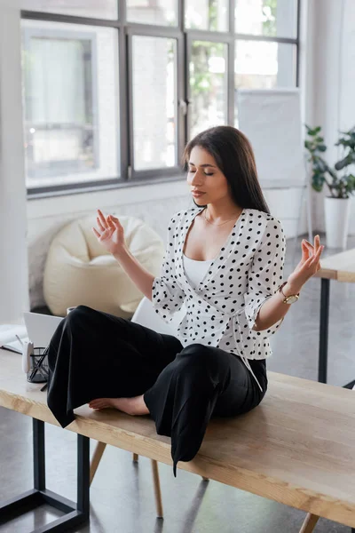 Beautiful businesswoman with closed eyes meditating in office — Stock Photo