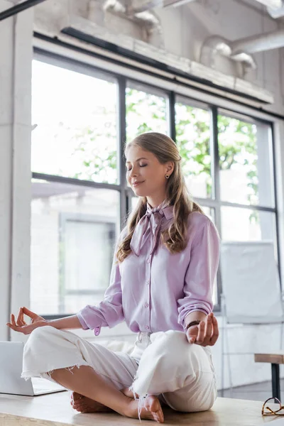 Cheerful businesswoman with closed eyes meditating in office — Stock Photo