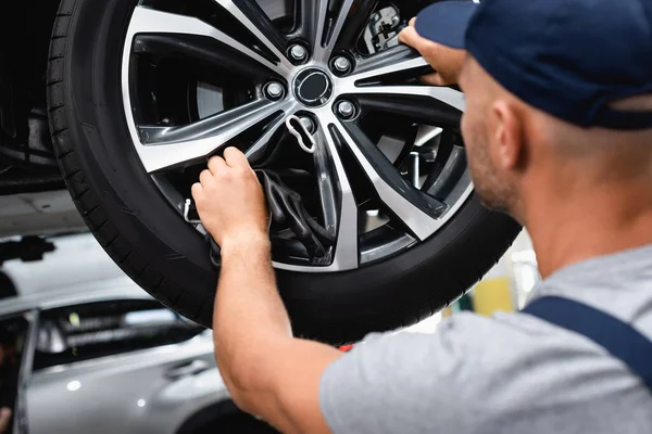Selektiver Fokus des Technikers, der die Radscheibe berührt, während er das Auto fixiert — Stockfoto