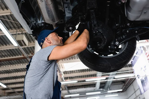 Niedrige Winkelansicht des Technikers in der Kappe Reparatur Auto in der Tankstelle — Stockfoto