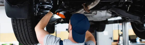 Orientación panorámica del mecánico en el casquillo que sostiene la linterna y la reparación de coches en la estación de servicio - foto de stock