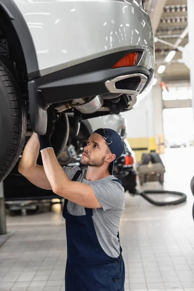 Foyer sélectif de beau mécanicien en uniforme et fixation de capuchon voiture — Photo de stock