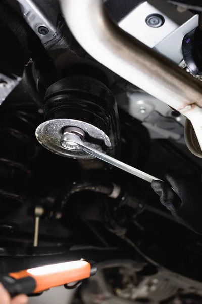 Cropped view of mechanic holding wrench and flashlight while fixing vehicle — Stock Photo