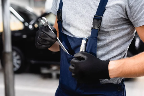 Ausgeschnittene Ansicht des Mechanikers in Overalls, der Schraubenschlüssel aus der Tasche nimmt — Stockfoto