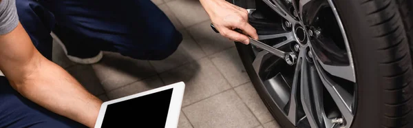 Coltura orizzontale del meccanico che tiene tablet digitale con schermo bianco vicino collaboratore con chiave riparazione auto — Foto stock