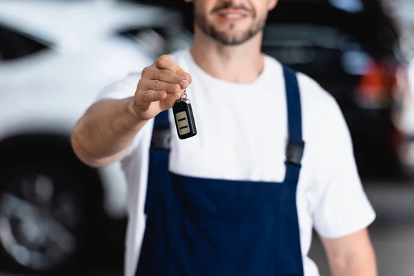 Selective focus of cheerful mechanic in uniform holding car key — Stock Photo