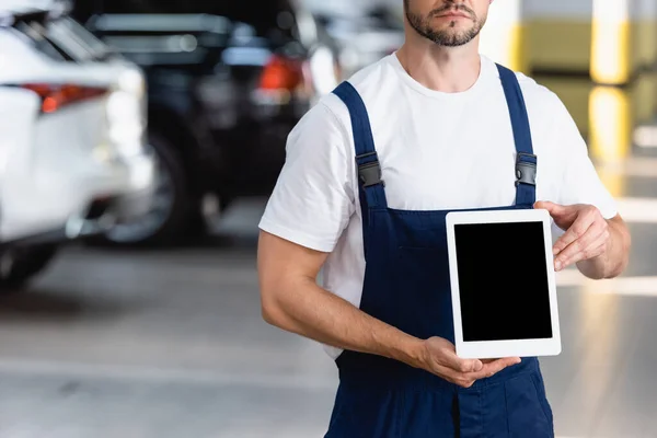 Vista ritagliata del meccanico in uniforme e cappuccio con tablet digitale con schermo bianco in officina — Foto stock