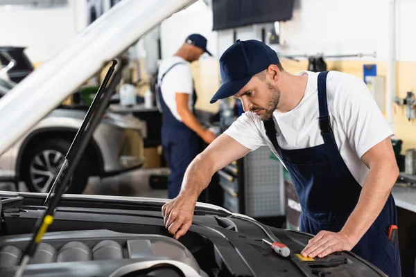 Selektiver Fokus des Mechanikers in der Haubenreparatur neben dem Mitarbeiter in der Werkstatt — Stockfoto