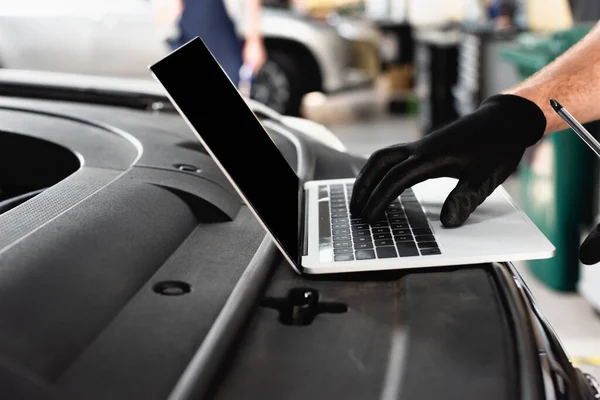 Vista recortada de mecanografía automática en el ordenador portátil con pantalla en blanco en el coche en la estación de servicio - foto de stock