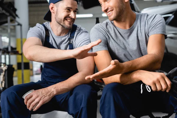 Happy auto mechanics sitting and clapping hands at service station — Stock Photo