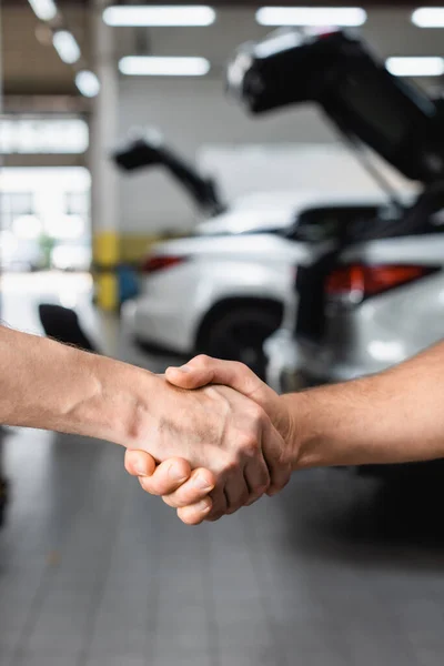 Selective focus of handshake gesture of men at service station — Stock Photo