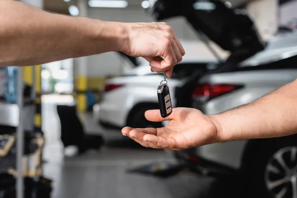 Selective focus of man receiving car key at service station — Stock Photo