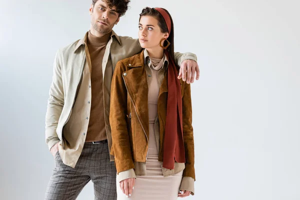 Handsome man holding hand on shoulder of fashionable woman isolated on grey — Stock Photo