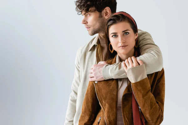 Attraente, ragazza alla moda guardando la fotocamera mentre bello uomo abbracciando il suo isolato sul grigio — Foto stock