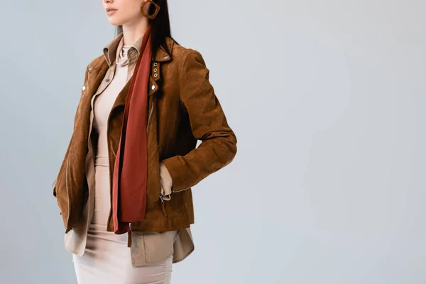 Cropped view of stylish girl in suede jacket posing with hands in pockets isolated on grey — Stock Photo