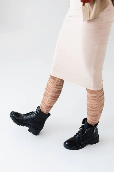 Cropped view of girl in stylish striped tights and black boots on white — Stock Photo