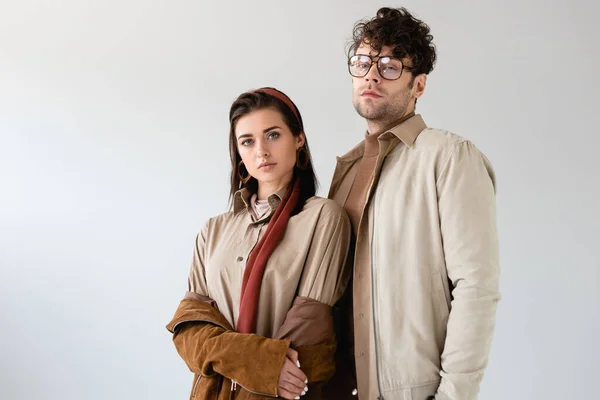 Fashionable couple in autumn clothes looking at camera while posing isolated on grey — Stock Photo