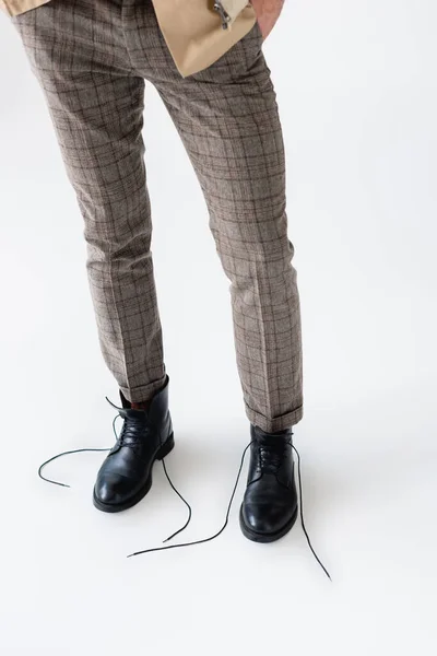 Visão parcial de pernas masculinas em calças na moda e botas pretas não atadas em branco — Fotografia de Stock