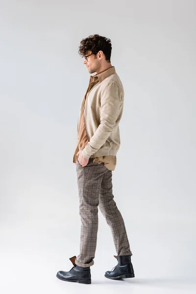 Vue latérale de l'homme à la mode en vêtements d'automne posant avec les mains dans les poches sur le gris — Stock Photo