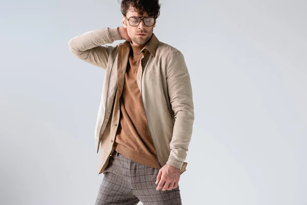 Fashionable man in eyeglasses touching hair while posing with closed eyes isolated on grey — Stock Photo