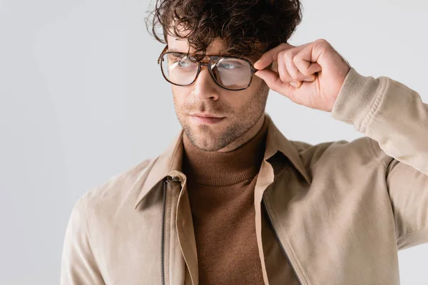 Красивий, стильний чоловік торкається окулярів, дивлячись ізольовано на сірий — стокове фото
