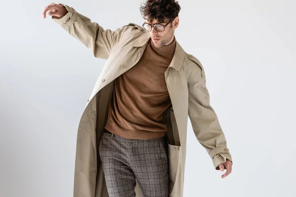 Молодий чоловік в модному осінньому вбранні балансує ізольовано на сірому — стокове фото