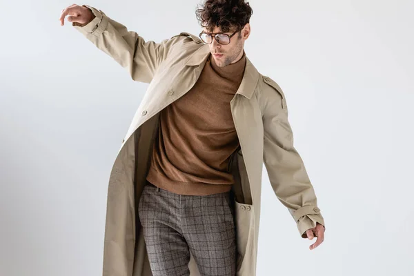 Young man in trendy autumn outfit balancing isolated on grey — Stock Photo