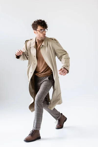 Homem na moda, assustado correndo e olhando para trás isolado em cinza — Fotografia de Stock