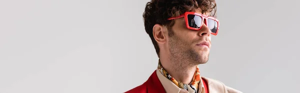 Panoramaaufnahme eines selbstbewussten, stylischen Mannes mit Sonnenbrille, der isoliert auf grau blickt — Stockfoto