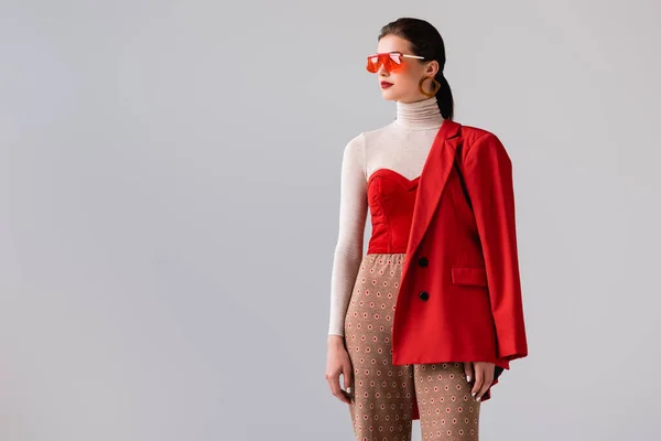 Beautiful, stylish girl in sunglasses looking away while posing isolated on grey — Stock Photo