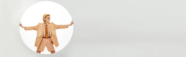 Orientación panorámica de la chica de moda sonriente tocando agujero redondo sobre fondo blanco - foto de stock