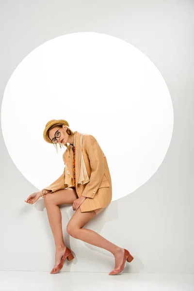 Mujer joven y elegante posando en agujero redondo sobre fondo blanco - foto de stock