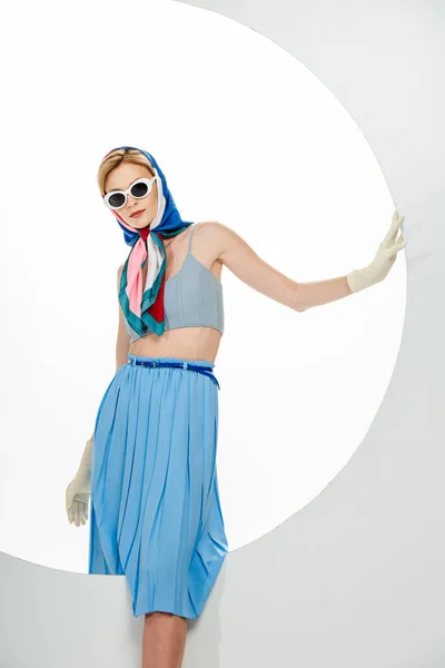 Femme élégante en gants et foulard posant près du trou rond sur fond blanc — Photo de stock